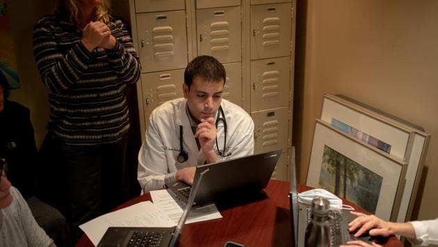 Dr. William Jason Sulaka, 40, a physician with Infinity Primary Care, looks at his computer as Dorene Blain, an Information Technology Support Analyst, leads a tutorial session on how to conduct virtual appointments through OTTO Health, a technology software which allows medical professionals to video chat with their patients, in West Bloomfield Township, Michigan. “I would rather see a patient in the office ... I prefer real visits to virtual visits,” Sulaka said. (REUTERS / Emily Elconin )