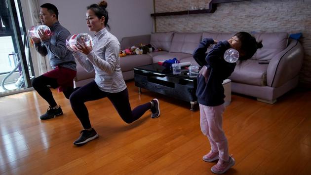Dino Lin, Stella Zhang and Wowo Lin, 5, exercise using filled water bottles as weights as they watch a fitness class online at their house, during the outbreak, in Shanghai, China. “We have been staying at home mostly. We are not forced to do so but believe this is the best way to keep our family away from infection,” said Dino Lin. (Aly Song / REUTERS)