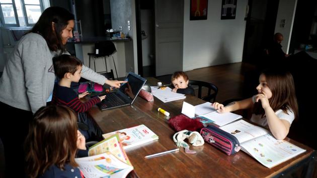 Marina Brebion, a French school teacher, helps her four children with school work,during an imposed lockdown to prevent the spread of the novel coronavirus disease (COVID-19) outbreak, in Nantes, France. "We respect the lockdown instruction as much as possible," Brebion said. "For now, the confinement remains quite flexible, we can go out for the imperatives, like shopping." (REUTERS / Stephane Mahe)
