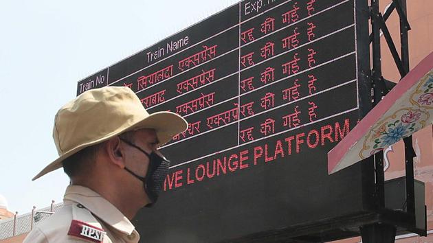 A railway police personnel stands next to a screen showing cancelled trains at Jaipur Railway Station on Sunday, as Rajasthan takes part in Janta Curfew.(Himanshu Vyas/HT Photo)