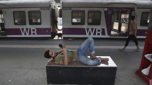 A man relaxes looking at his phone at a deserted train platform in Mumbai. (AP)