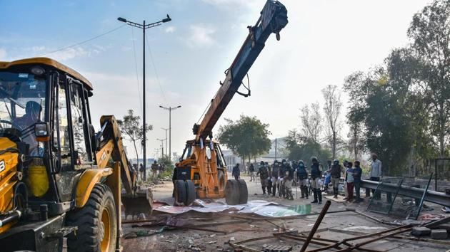 Police personnel use earth movers to clear the protest site. (PTI)