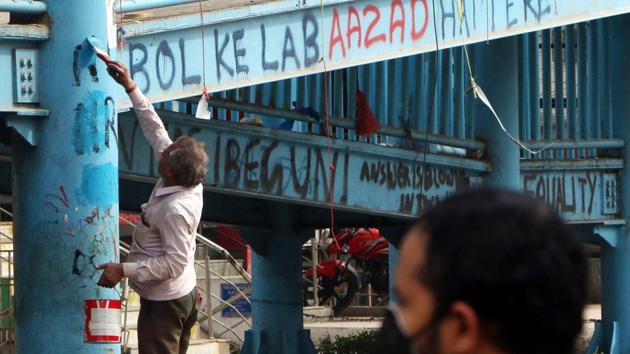 MCD workers paint to cover up anti-CAA slogans at Shaheen Bagh after the protest site was cleared during the second day of lockdown imposed by the state government to curb the spread of coronavirus, in New Delhi, Tuesday, March 24, 2020. (Salman Ali / HT Photo)