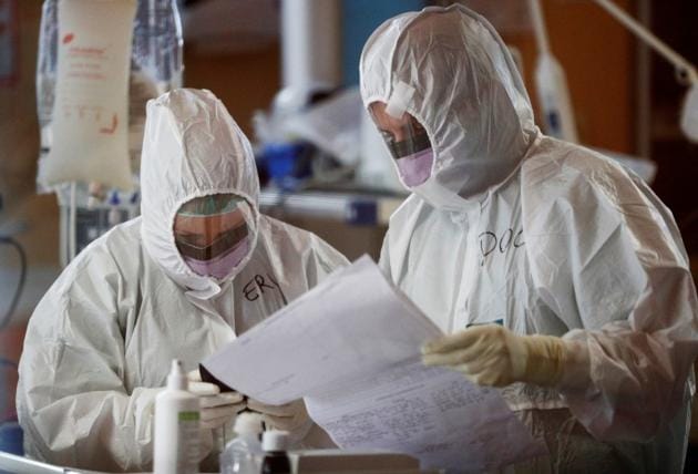 Medical workers in protective suits check a document as they treat patients suffering with coronavirus disease (COVID-19) in an intensive care unit at the Casalpalocco hospital, a hospital in Rome that has been dedicated to treating cases of the disease, Italy, March 24, 2020.(Reuters Photo)