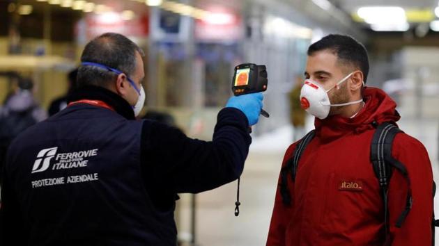 A train security staff member checks the temperature of a passenger arriving from Turin and Milan by train at Naples Central station as Italy ramps up measures to slow the spread of coronavirus disease (COVID-19) in Naples, Italy. (REUTERS)