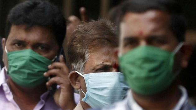 Men wearing protective masks walk inside the premises of a hospital where a special ward has been set up for the coronavirus disease. (REUTERS)