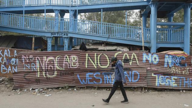 A man walks past slogans painted on discarded tin sheds near a site of the protest against Citizenship Amendment Act (CAA), at Shaheen Bagh, Jamia Nagar in New Delhi in January 2020.(Burhaan Kinu/HT File Photo)