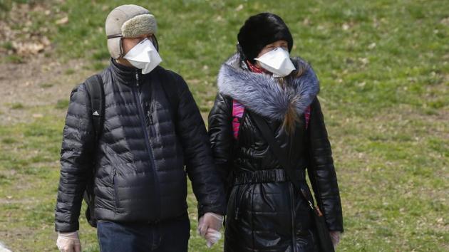 A couple wears face masks and surgical gloves as they walk in Central Park. “I’m scared for me and patients that this could go on” for months, Lauren, a psychologist who declined to give her surname told AFP. Anxiety and depression “all gets heightened at a time like this,” she added, one of the few souls out and about on Manhattan’s Upper East Side on Monday. (Kena Betancur / AFP)