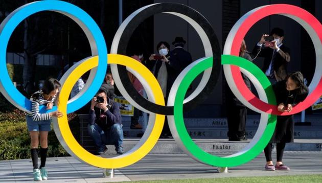Visitors wearing protective face masks following an outbreak of the coronavirus disease (COVID-19) are seen through the Olympic rings in front of the Japan Olympics Museum, a day after the announcement of the games' postponement to 2021, in Tokyo, Japan March 25, 2020. (Reuters photo) Visitors wearing protective face masks following an outbreak of the coronavirus disease (COVID-19) are seen through the Olympic rings in front of the Japan Olympics Museum, a day after the announcement of the games' postponement to 2021, in Tokyo, Japan March 25, 2020. (Reuters photo)