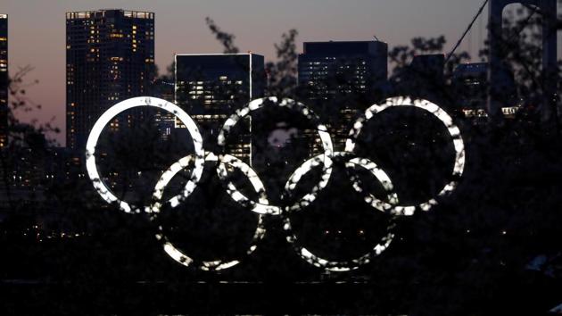 The giant Olympic rings are seen in the dusk through a tree at the waterfront area at Odaiba Marine Park.(REUTERS)