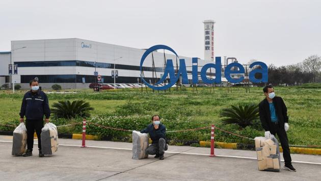 Workers wearing protective masks are seen outside Midea factory, which has resumed operations in Wuhan on March 25, 2020. While many migrant workers remain trapped by travel bans, industrial production has returned to action, including in the crucial auto manufacturing industry, which is largely based in Wuhan, and in businesses that provide critical links in global supply chains. (REUTERS)