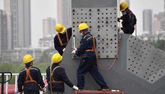 Workers wearing protective masks work on a bridge after the construction works resumed, following the novel coronavirus disease (COVID-19) outbreak, in Wuhan, Hubei province, China March 24, 2020. China Daily via REUTERS
