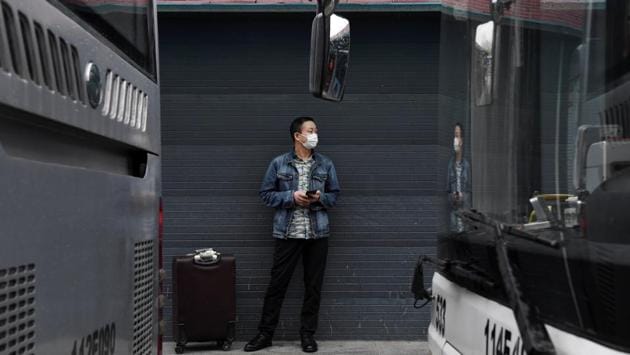 A man wearing a protective mask stands next to a suitcase at a bus terminal in Wuhan. The Chinese government says work has restarted on about 90% of major public construction projects across the country, excluding Hubei province and its capital, Wuhan, where the virus was first detected in December. (REUTERS)