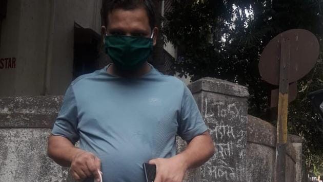 A volunteer from Project Mumbai carries grocery bags with the tagline - Mumbai ke liye kuch bhi karega