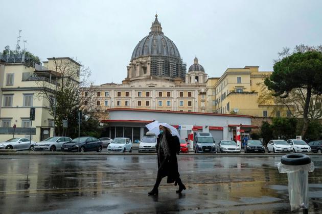 A woman wearing aface mask walks across a street past the Vatican's Santa Marta residence (Rear C) as seen with St. Peter's basilica from Rome on March 26, 2020 during the country's lockdown following the COVID-19 new coronavirus pandemic. An Italian employee of the Holy See who lives in the same residence as Pope Francis was reported on March 26, 2020 to have tested positive for COVID-19 and has been hospitalised. (AFP) A woman wearing aface mask walks across a street past the Vatican's Santa Marta residence (Rear C) as seen with St. Peter's basilica from Rome on March 26, 2020 during the country's lockdown following the COVID-19 new coronavirus pandemic. An Italian employee of the Holy See who lives in the same residence as Pope Francis was reported on March 26, 2020 to have tested positive for COVID-19 and has been hospitalised. (AFP)