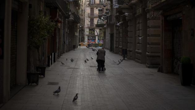 A woman pushes a cart with her belongings as she walks along an empty street in downtown Barcelona. Those sleeping rough in Barcelona agree on one thing: panhandling for money or food is pointless now because there’s nobody around to give them anything. (Emilio Morenatti / AP) A woman pushes a cart with her belongings as she walks along an empty street in downtown Barcelona. Those sleeping rough in Barcelona agree on one thing: panhandling for money or food is pointless now because there’s nobody around to give them anything. (Emilio Morenatti / AP)