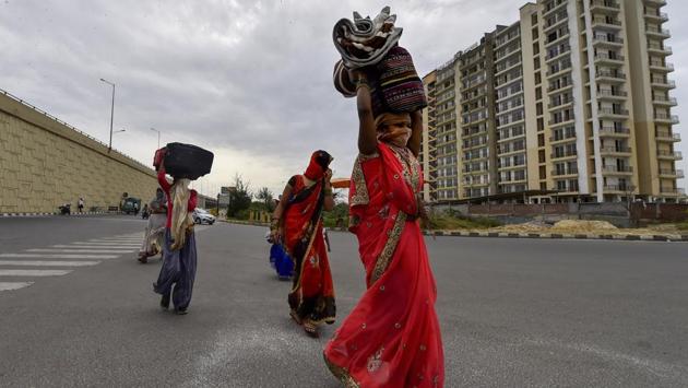 A group of migrant workers, their belongings bundled atop their heads, walk home, on the NH24 near Delhi-UP Border in New Delhi. Some of them have cooking gas stoves with them, others are begging on the way, and the rest are trying to suppress their hunger while they desperately look for any mode of transport to get back home. (Ravi Choudhary / PTI)