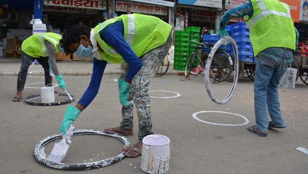 MC staff demarcating the space for customers to queue up while ensuring social distancing outside shops in Panchkula.(Sant Arora/HT) MC staff demarcating the space for customers to queue up while ensuring social distancing outside shops in Panchkula.(Sant Arora/HT)