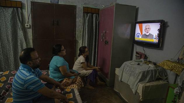 A family watches Prime Minister Narendra Modi address the nation in a televised speech about COVID-19 situation, in Gauhati, India.(AP)