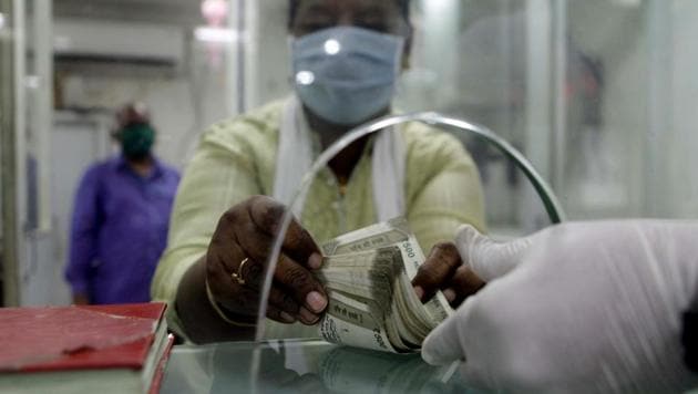 A customer wearing mask counts the money in the Bank as a precuationary measure against coronavirus, amid the lockdown, in Mumbai on Friday. (ANI photo) A customer wearing mask counts the money in the Bank as a precuationary measure against coronavirus, amid the lockdown, in Mumbai on Friday. (ANI photo)