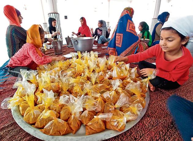 Children helping out in packing food, to be distributed among the needy and homeless, at the Sector 19 gurdwara in Chandigarh. Each of the 5,000 packets dispatched by gurdwaras in the tricity had three chapatis and one cooked vegetable.(RAVI KUMAR/HT)