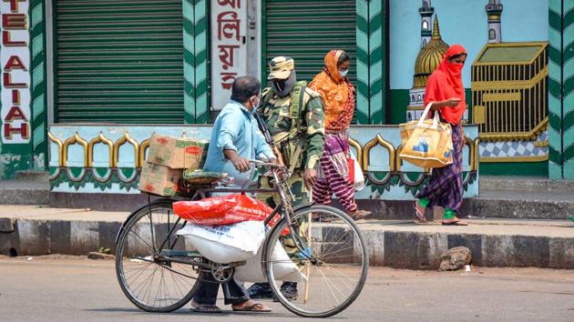 A security personnel checks a man carrying sacks of essential items on a bicycle in Guwahati during the lockdown to fight the coronavirus pandemic. (PTI) A security personnel checks a man carrying sacks of essential items on a bicycle in Guwahati during the lockdown to fight the coronavirus pandemic. (PTI)