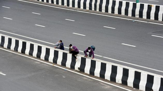A trio of migrant workers jump a road divider on the Delhi-Meerut highway while journeying onwards in New Delhi. (Raj K Raj / HT Photo) A trio of migrant workers jump a road divider on the Delhi-Meerut highway while journeying onwards in New Delhi. (Raj K Raj / HT Photo)