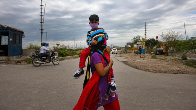 Mamta, 32, carries her 5 year old son Yuvraj as they head toward their home town Aligarh on the third day of the 21-day national lockdown imposed by Prime Minister Narendra Modi to curb the spread of coronavirus, at Ghazipur, in New Delhi. (Amal KS / HT Photo)