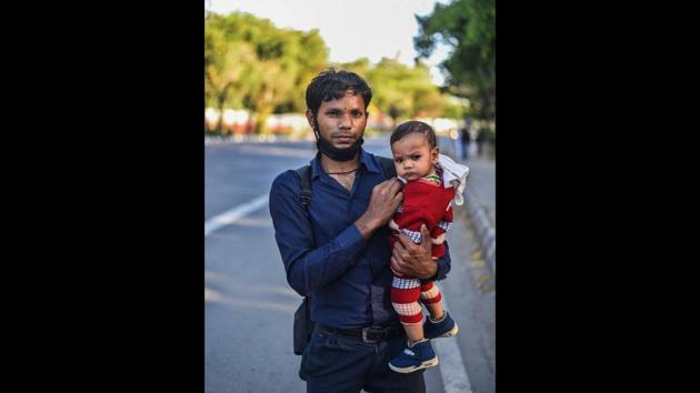 Kishan, a rickshaw puller, 24, with his nine-month-old son while walking to Mahoba in UP from Ashram in New Delhi, India, on Saturday, March 28. He said he had 1500 rupees for the journey that he was making with his wife and son. He also mentioned that he would never return to Delhi. (Biplov Bhuyan / HT Photo) Kishan, a rickshaw puller, 24, with his nine-month-old son while walking to Mahoba in UP from Ashram in New Delhi, India, on Saturday, March 28. He said he had 1500 rupees for the journey that he was making with his wife and son. He also mentioned that he would never return to Delhi. (Biplov Bhuyan / HT Photo)