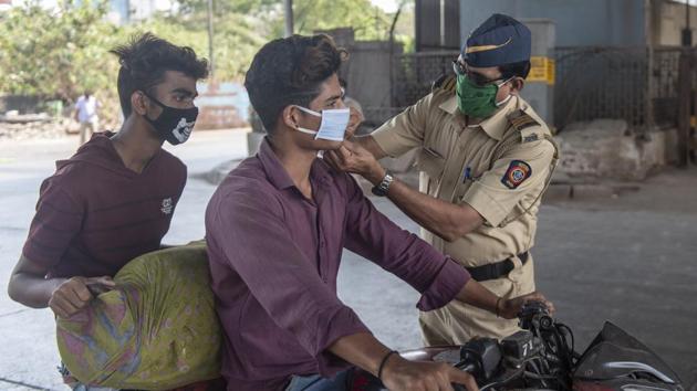 A policeman helps a boy fix his mask during Nakabandi at Kurla Signal, Eastern express highway in Mumbai during the lockdown due to coronavirus pandemic. (Aalok Soni/HT Photo) A policeman helps a boy fix his mask during Nakabandi at Kurla Signal, Eastern express highway in Mumbai during the lockdown due to coronavirus pandemic. (Aalok Soni/HT Photo)