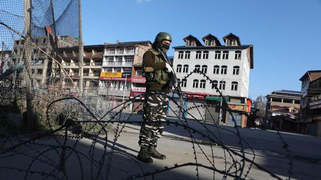 A paramilitary soldier stands guard next to concertina barbed wire, on day 5 of the 21 day nationwide lockdown imposed by PM Narendra Modi to check the spread of coronavirus, in Srinagar.(Waseem Andrabi / Hindustan Times)