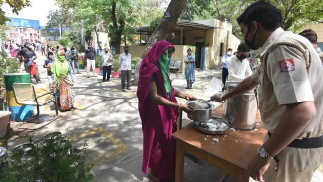 People queue for food being distributed by the Delhi government and served by policemen, while observing social distancing at the Rajkiya Pratibha Vikas Vidyalaya, Gandhi Nagar, in New Delhi. (Sonu Mehta / HT PHOTO)
