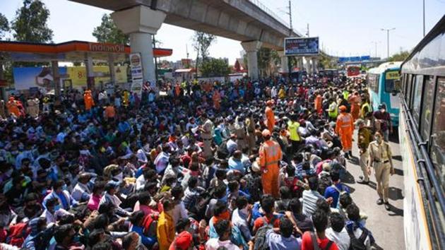 Disaster management personnel offers hand sanitizer to migrant workers at the Anand Vihar Bus Terminus, March 29, 2020(Amal KS/HT PHOTO)