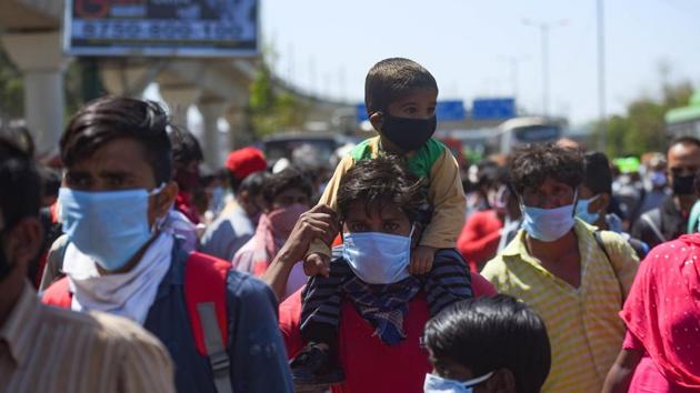 A man seen carrying a child on his shoulder as a large number of migrant workers head home on day 5 of the 21 day nationwide lockdown to curb the spread of coronavirus.(Amal KS/HT PHOTO)