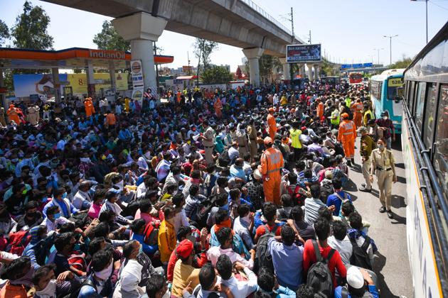 NDRF personnel offers hand sanitizer to migrant workers assembled outside Anand Vihar Bus Terminus on Day 5 of the 21-day nationwide lockdown imposed by PM Narendra Modi to curb the spread of coronavirus, in New Delhi, India, on Sunday, March 29, 2020.(Amal KS/HT PHOTO)