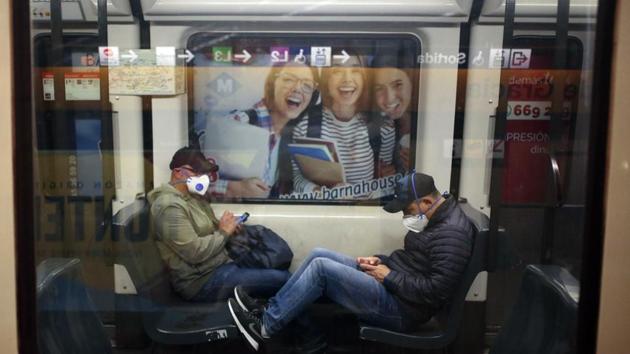 Two passenger wearing protective masks sit inside a train in Barcelona, Spain. The country has entered its third week under near-total lockdown on Sunday, as the government approved a strengthening of measures and the death toll crossed 6,500. (Joan Mateu / AP) 