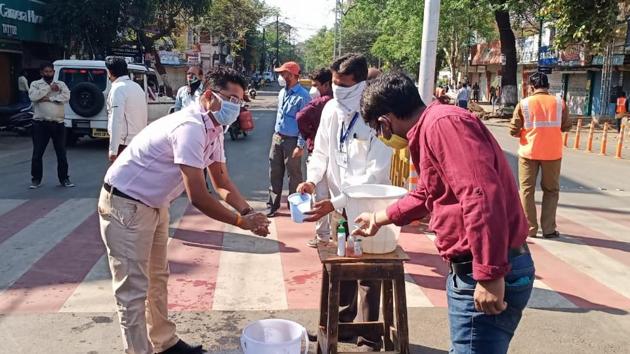 Locals helping a person wash hands in Sagar after siren is blown on Monday. (HT Photo) Locals helping a person wash hands in Sagar after siren is blown on Monday. (HT Photo)