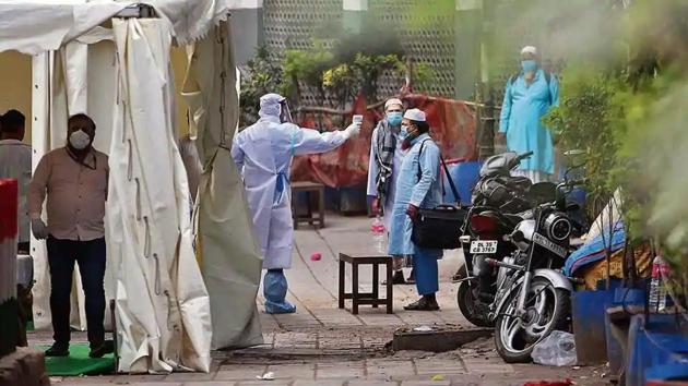 A volunteer wearing protective suit checks temperature of a man at Nizamuddin during coronavirus lockdown in New Delhi.(ANI)