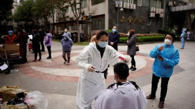 Barber Xiong Juan, 39, cuts a customer's hair at a residential compound in Wuhan. Xiong, 39, now spends her days riding around on her electric bicycle and offering her services to local residents who like her were stuck at home after authorities ordered the lockdown. (Aly Song / REUTERS)