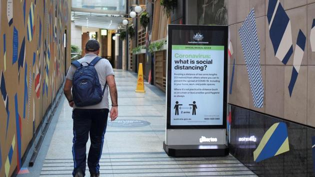 A man walks in a corridor near a sign with instructions about the coronavirus and social distancing in Sydney, on March 31.(Reuters Photo)