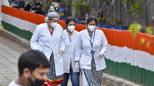 Medics, wearing masks, walk as the police cordoned off an area in Nizamuddin after some people showed coronavirus symptoms, in New Delhi.(PTI)