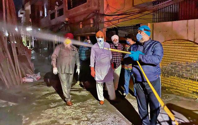 MC secretary Jasdev Sekhon (blue gear) spray disinfectant in the area where victim lived in Amarpura(HT Photo)