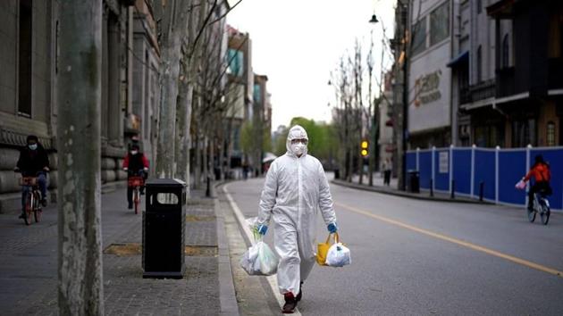 A man wearing a hazmat suit walks on a street in Wuhan, Hubei province of China amid coronavirus outbreak.(REUTERS)