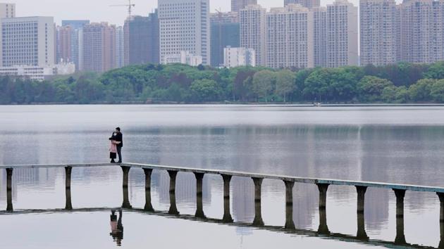 People wearing face masks hug on the East Lake in Wuhan, Hubei province. The city, at the centre of China’s outbreak was reopening for business Monday after authorities lifted more of the controls that locked downs tens of millions of people for two months. (Aly Song / REUTERS)