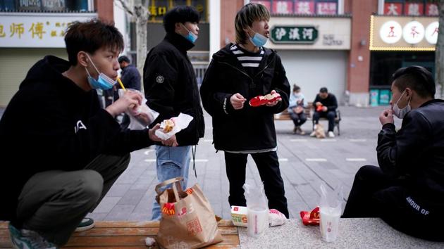 People with face masks eat outside a McDonald's restaurant in Wuhan on March 30. President Xi Jinping visited Wuhan for the first time on March 10 in a show of official confidence that the virus was under control. The next day, the government began to ease controls on Hubei, allowing some factories and other businesses deemed essential to reopen. (Aly Song / REUTERS)