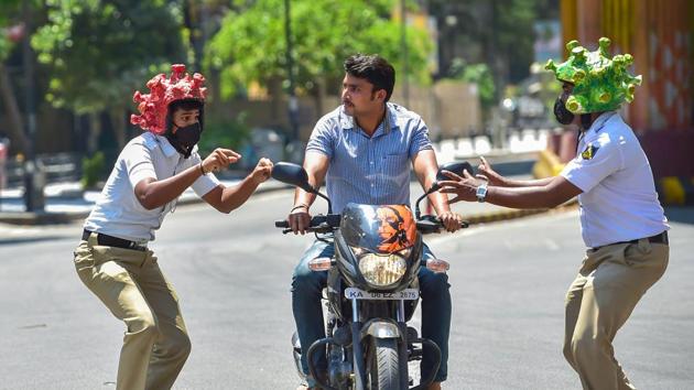 Policeman wearing coronavirus-themed helmets charge at bike rider during an awareness programme amid the nationwide lockdown in the wake of novel coronavirus pandemic, in Bengaluru, on March 31.(PTI Photo) Policeman wearing coronavirus-themed helmets charge at bike rider during an awareness programme amid the nationwide lockdown in the wake of novel coronavirus pandemic, in Bengaluru, on March 31.(PTI Photo)