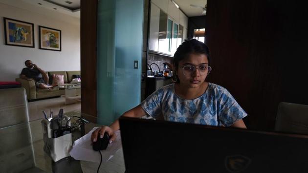 Khushbu Hitesh Mehta, an architecture student, works on her project as her father Hitesh Mehta, a businessman, speaks on his mobile phone, in Mumbai. Schools, offices and universities out of physical reach, cubicles and classrooms now occupy people’s homes. (Hemanshi Kamani / REUTERS)