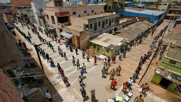People stand on lines drawn to maintain a safe distance as they wait to receive food being distributed by the Central Reserve Police Force (CRPF) during the lockdown in Chennai. Lockdown conditions have drawn public and individual responses to addressing the question of food security especially among the weaker sections of society. (P. Ravikumar / REUTERS)