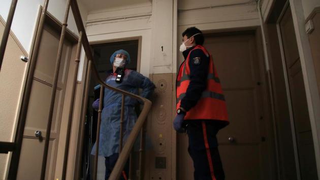 Cyril Lamriben (L), and Pierre Leroux wait outside an apartment before checking on a resident possibly infected with the Covid-19 virus. The volunteers, all trained, equip themselves for the crisis with protective gowns, head gear, masks and gloves when they head out on a mission, not knowing what they will encounter when the door opens. (Michel Euler / AP) Cyril Lamriben (L), and Pierre Leroux wait outside an apartment before checking on a resident possibly infected with the Covid-19 virus. The volunteers, all trained, equip themselves for the crisis with protective gowns, head gear, masks and gloves when they head out on a mission, not knowing what they will encounter when the door opens. (Michel Euler / AP)