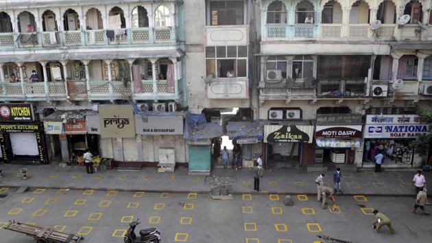 Civic workers mark positions for maintaining physical distance at market place in Mumbai. (AP) Civic workers mark positions for maintaining physical distance at market place in Mumbai. (AP)